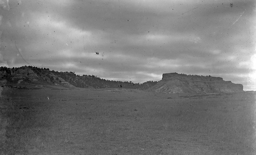 black and white photograph of landscape with bluffs in background