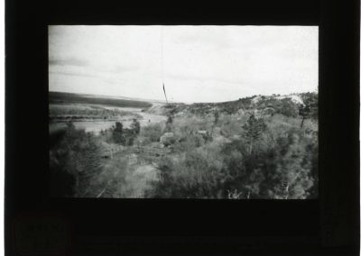 black and white lantern slide of landscape, home, along creek