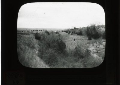 black and white lantern slide of landscape and landslide with one man on wagon tracks