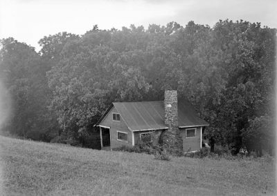 black and white photograph of a small house near trees