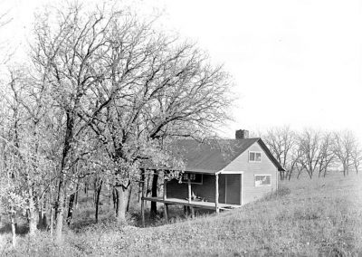 black and white photograph of a small house on bluff