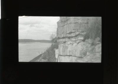 Black and white photograph of a rock cliff near railroad