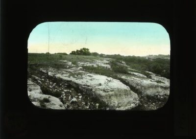 Black and white photograph with large rocks amid grass hand-colored green
