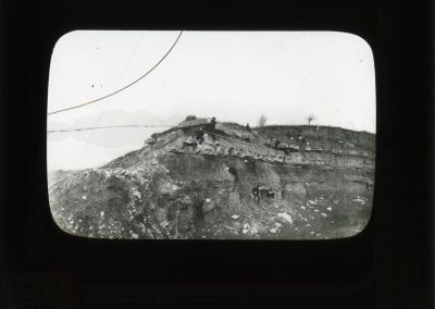 Black and white photograph of limestone on hillside with men looking at limestone