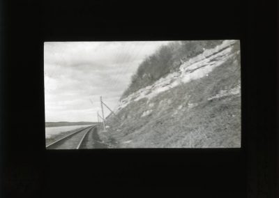 Black and white photo of limestone on side of hill with railroad lines