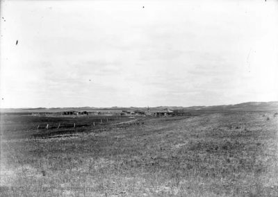 black and white photo of sod buildings and fences in open grassy landscape