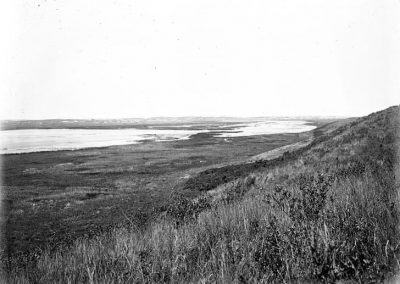 black and white photo of portion of a lake in grassy slopes