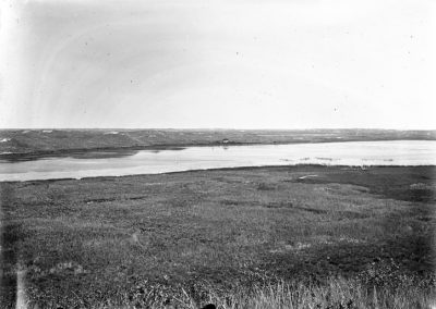 black and white photo of portion of a lake in grassy slopes