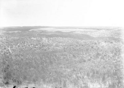 black and white photo of lake in far distance and grass land in foreground