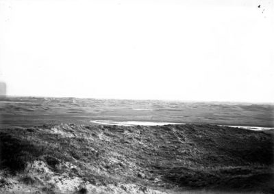 black and white photo of lake within grassy slopped land areas