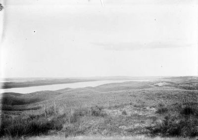 black and white photo of lakes in distance and sloping grass land in foreground
