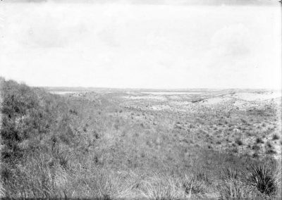 black and white photo of lake in far distance of open, sandy landscape