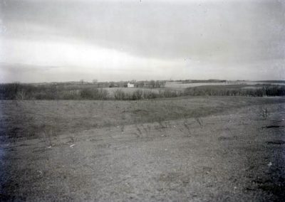 black and white photo of open landscape with house in far distance