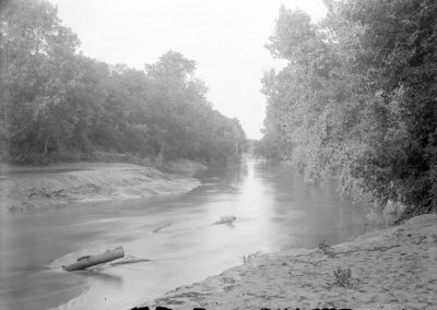 black and white photo of creek with embankment