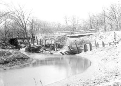 black and white photo of creek and bridge